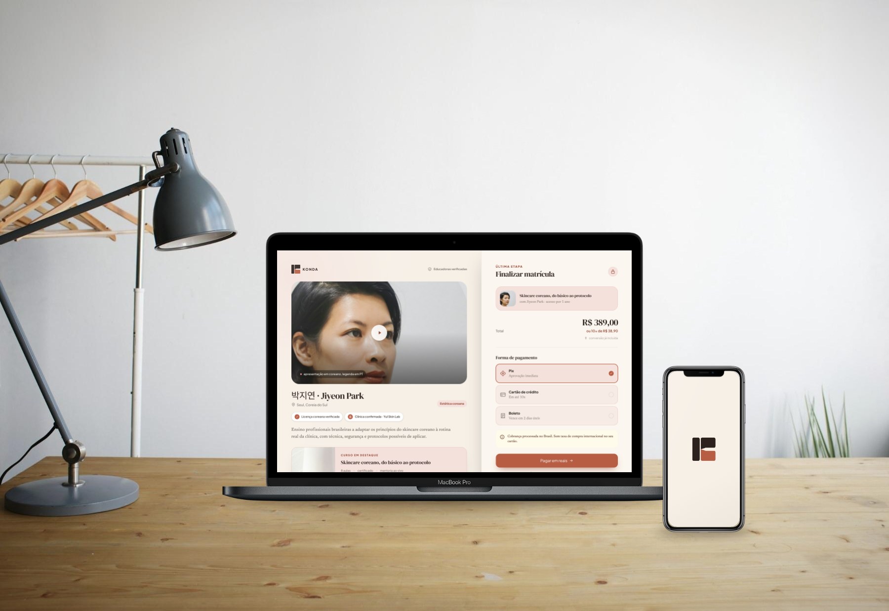 KONDA app on a laptop and the monogram on a phone, on a wooden desk